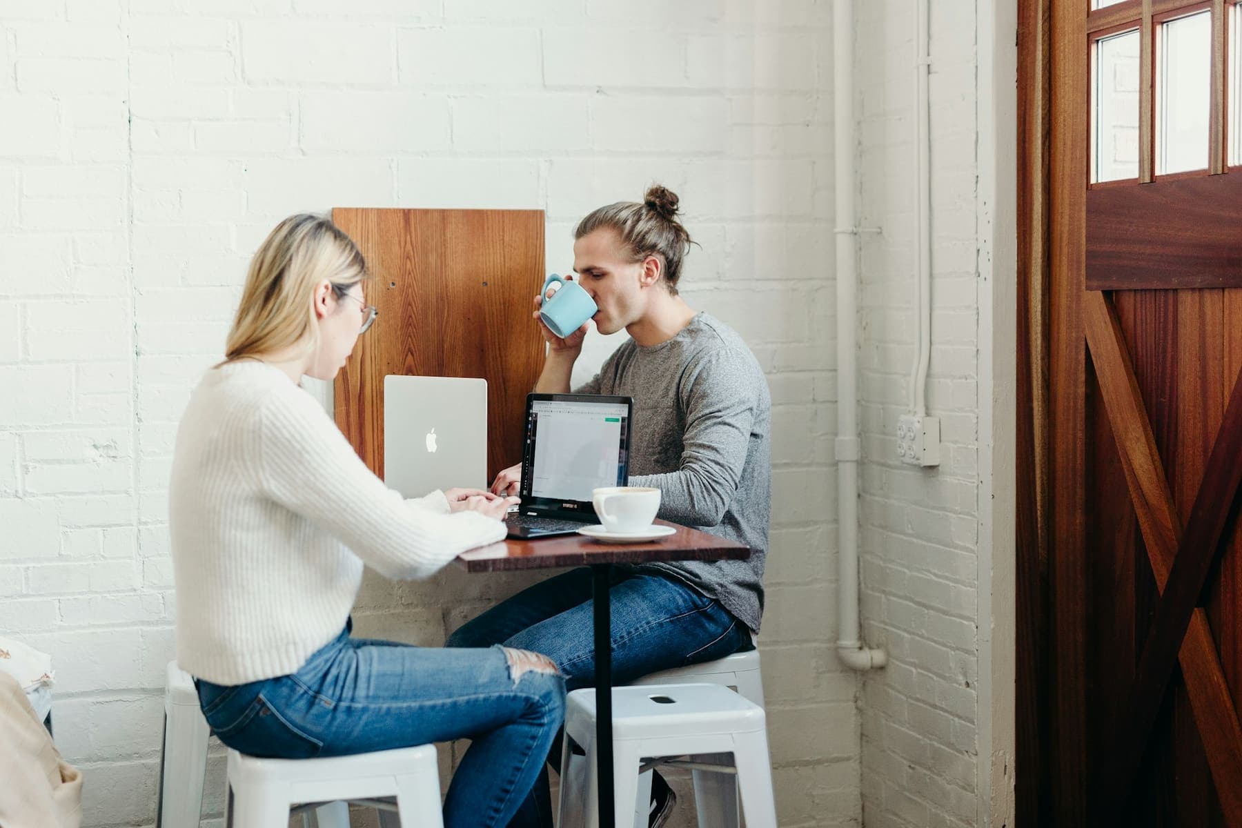 Two people talking over laptops at a café table